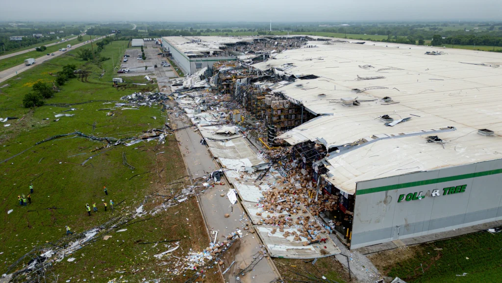 Dollar Tree warehouse with a collapsed roof and debris scattered after a tornado, disrupting supply chain operations.