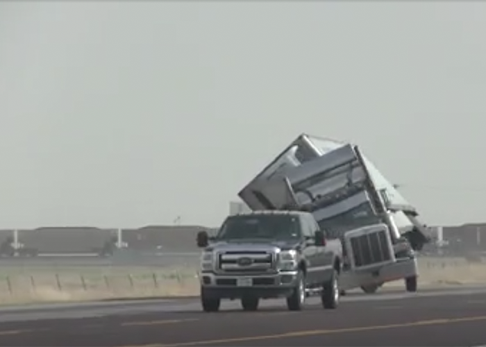 An overturned semi-truck on a stormy highway, highlighting the impact of severe weather on freight transportation.
